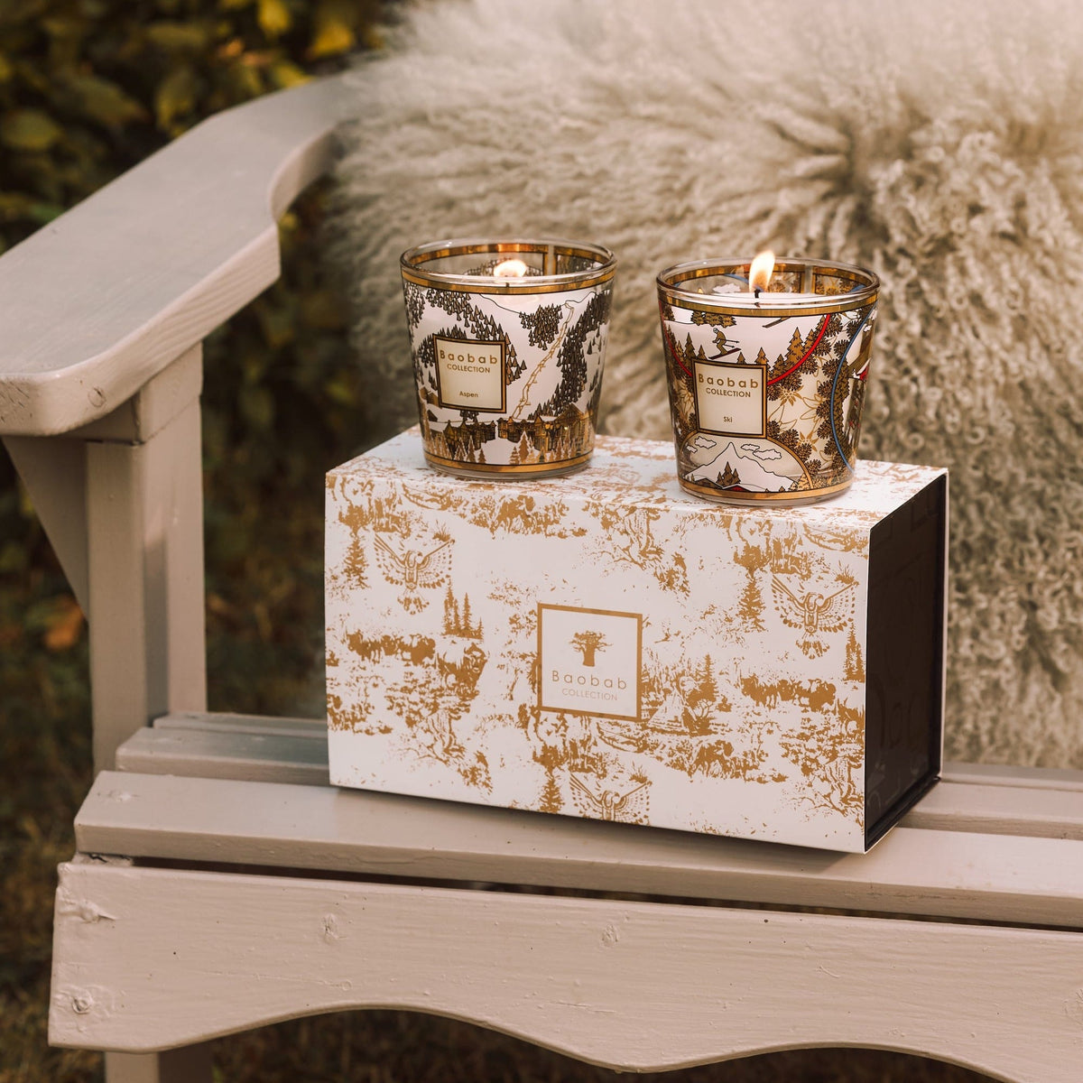 Baobab Candle Duo Ski & Aspen: two lit candles on their gold and white landscape-print gift box, 8 cm each