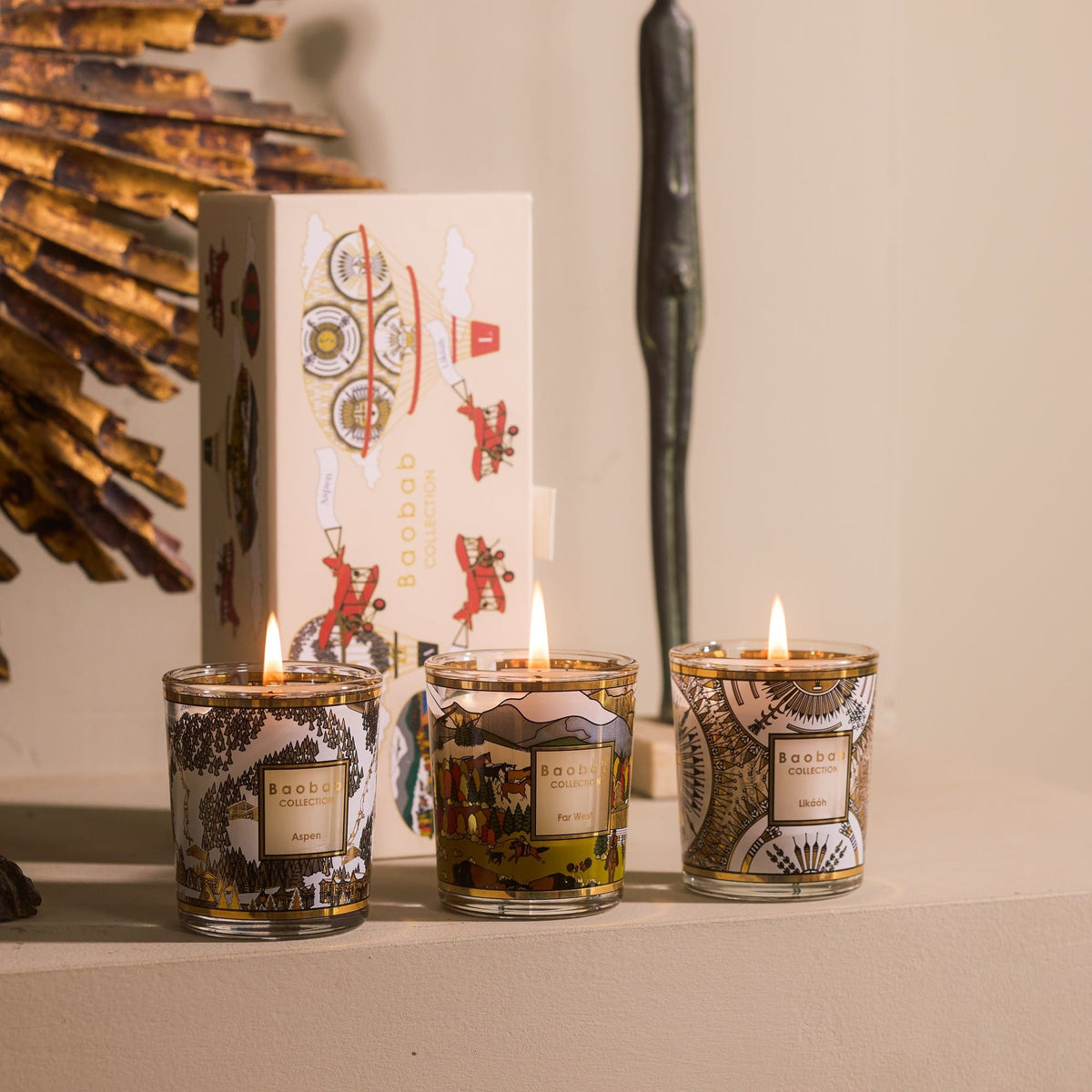 Baobab Trio Travel Candles Aspen, Likááh & Far West: three lit mini candles in gold-printed glass beside their gift box, 6 cm each