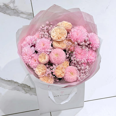 Baby Pink Blush Mini, Luxury: bouquet of pink chrysanthemums, peach garden roses and pink gypsophila in pink paper and a Daily Flowers carrier