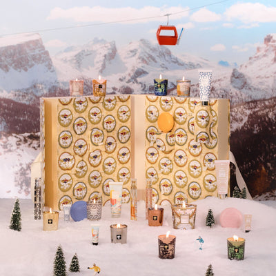 Baobab Advent Calendar Voyage Extraordinaire: opened gold book-shaped calendar with mini candles and body care in a snowy mountain scene, 24 doors