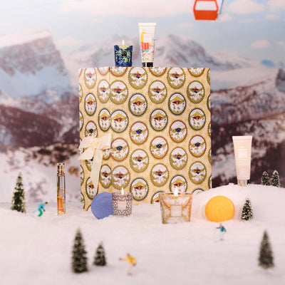 Baobab Advent Calendar Voyage Extraordinaire: closed gold medallion-print calendar with ribbon and miniatures in the snow, 24 doors