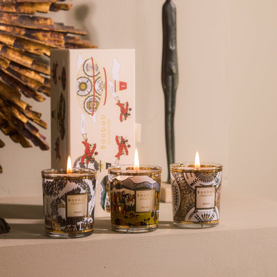 Baobab Trio Travel Candles Aspen, Likááh & Far West: three lit mini candles in gold-printed glass beside their gift box, 6 cm each